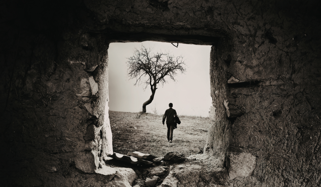 Man breaks through tunnel of cracked soil at dusk, symbolizing dark night of the soul transformation and spiritual rebirth.