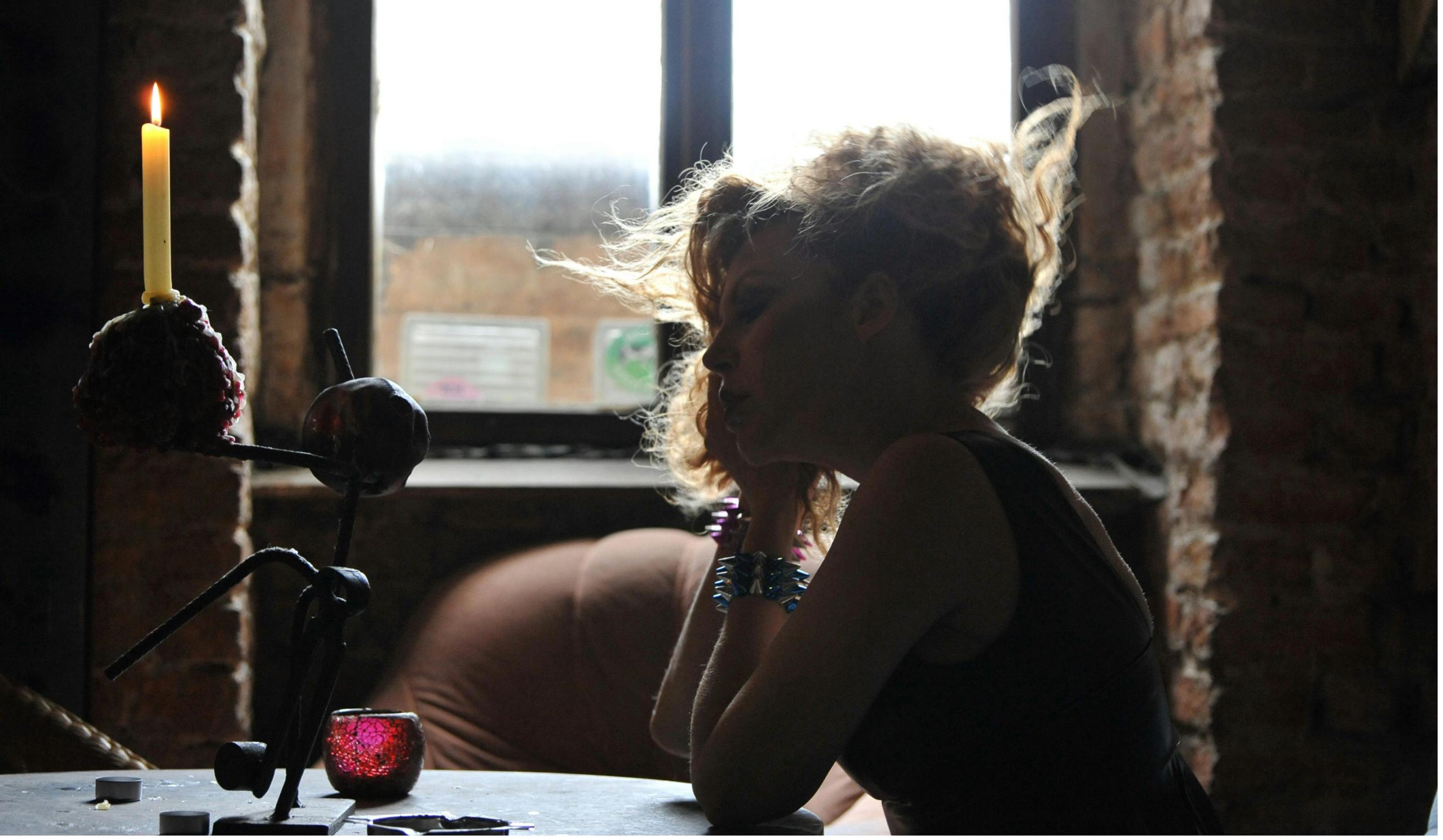 Woman reflecting in candlelight, looking numb, seeking healing from sexual shame.