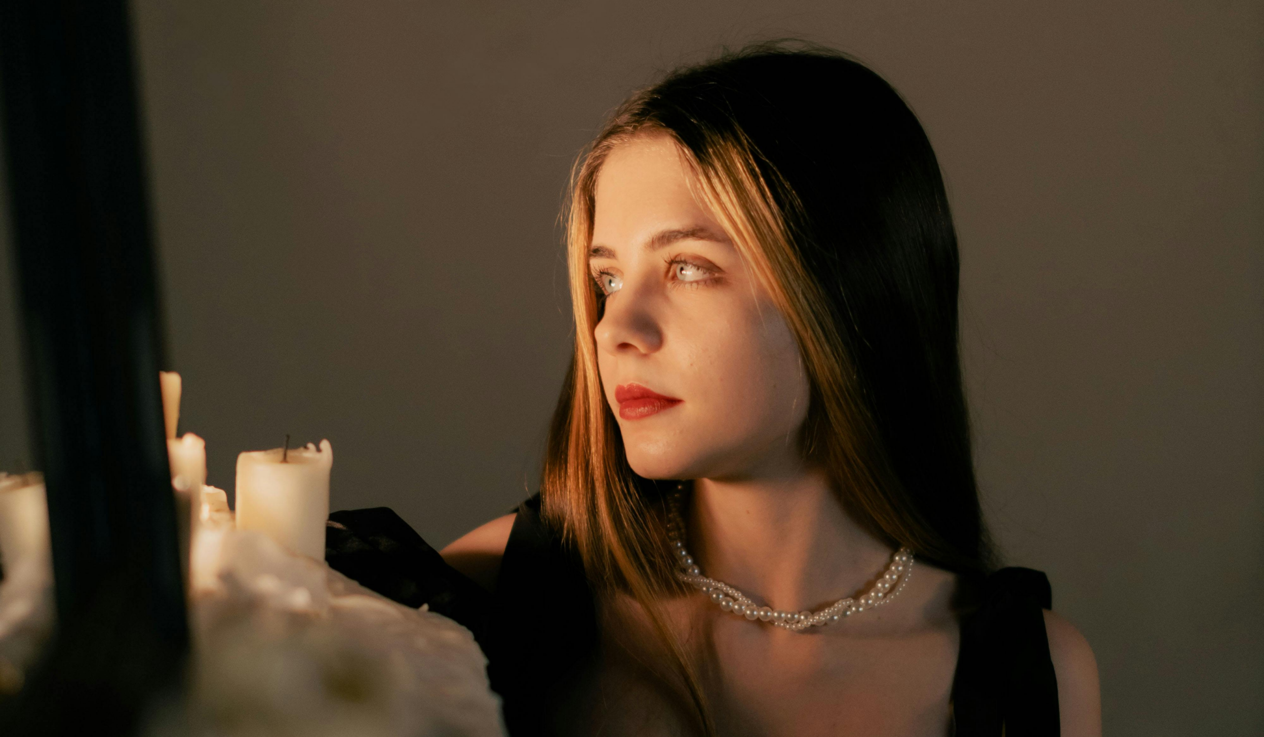 Woman in candlelit stillness, representing the difference between a managed spiritual life and a lived one.