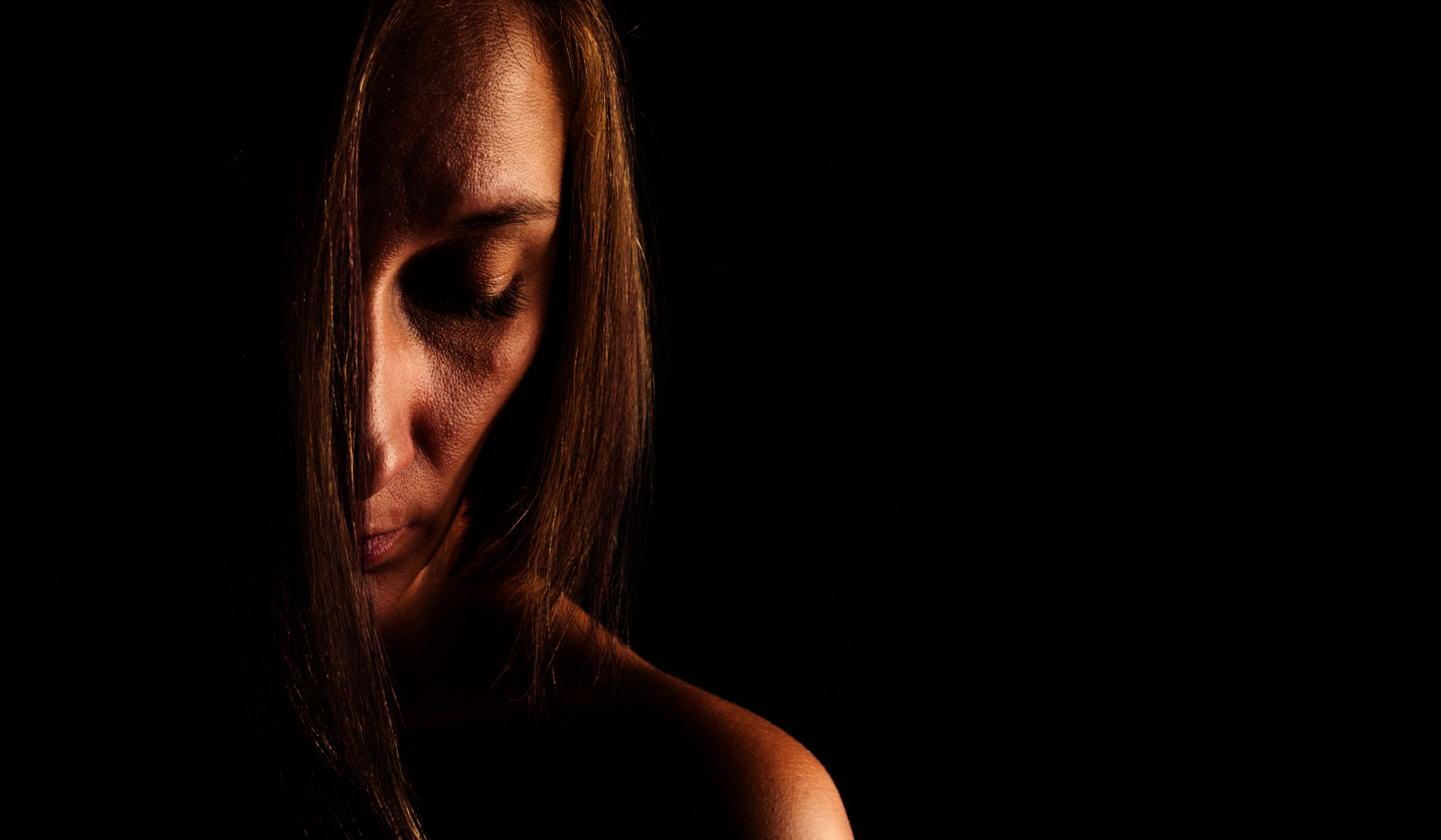 Woman standing still in dramatic gold light, embodying the uncomfortable tension of when sex feels like a chore.